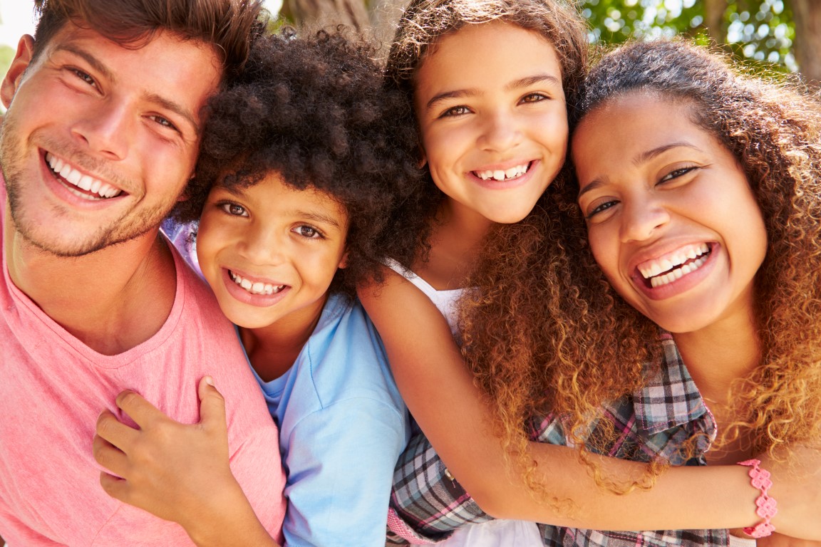 Parents Giving Children Piggyback Ride Outdoors